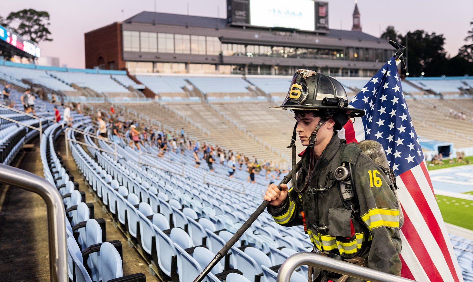 A firefighter holding an American flag and running up stadium steps.