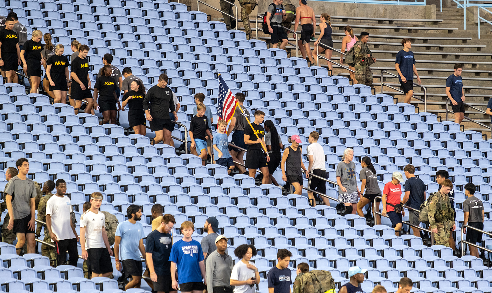 A large group of people, including some military members in army fatigues and black shirts reading 