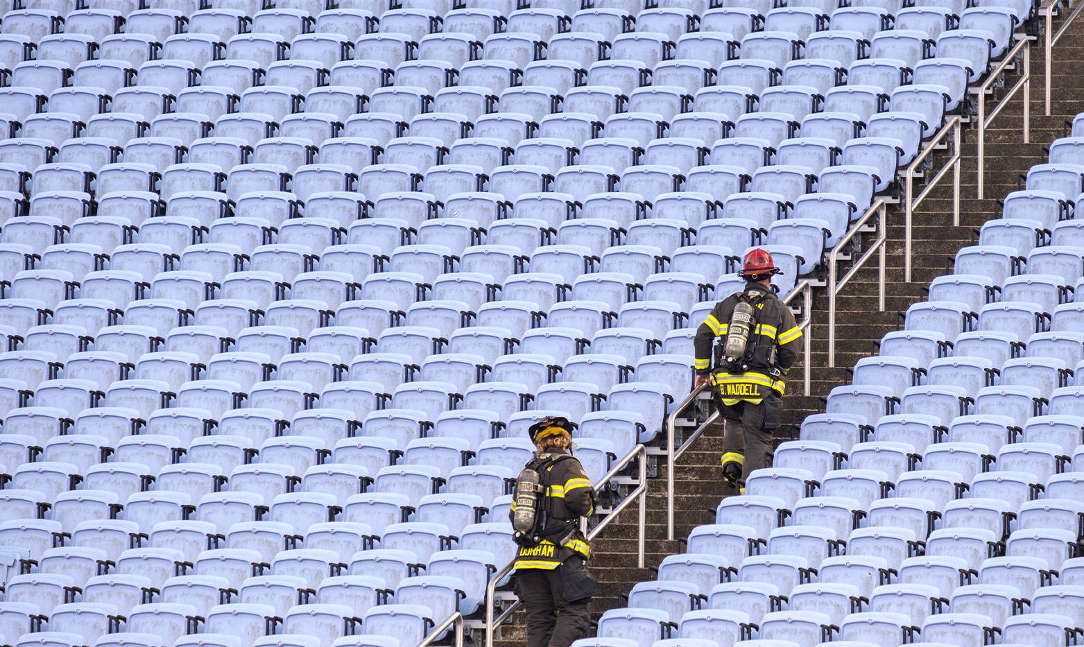 Two firefighters running up stadium stairs.