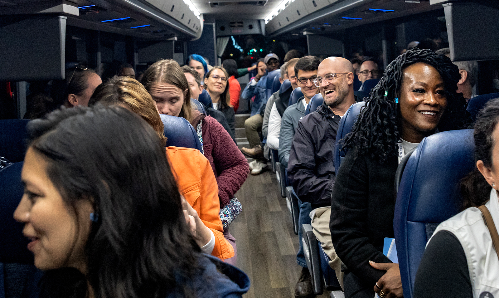 Rows of Tar Heel Bus Tour participants sitting on a bus and conversating with one another.