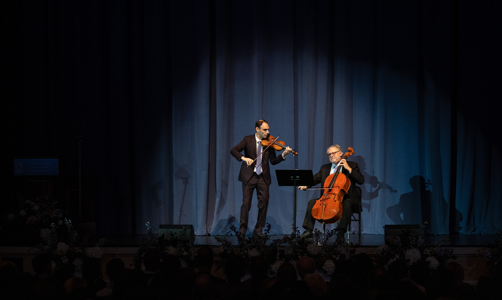 Two men playing the cello and violin on stage.