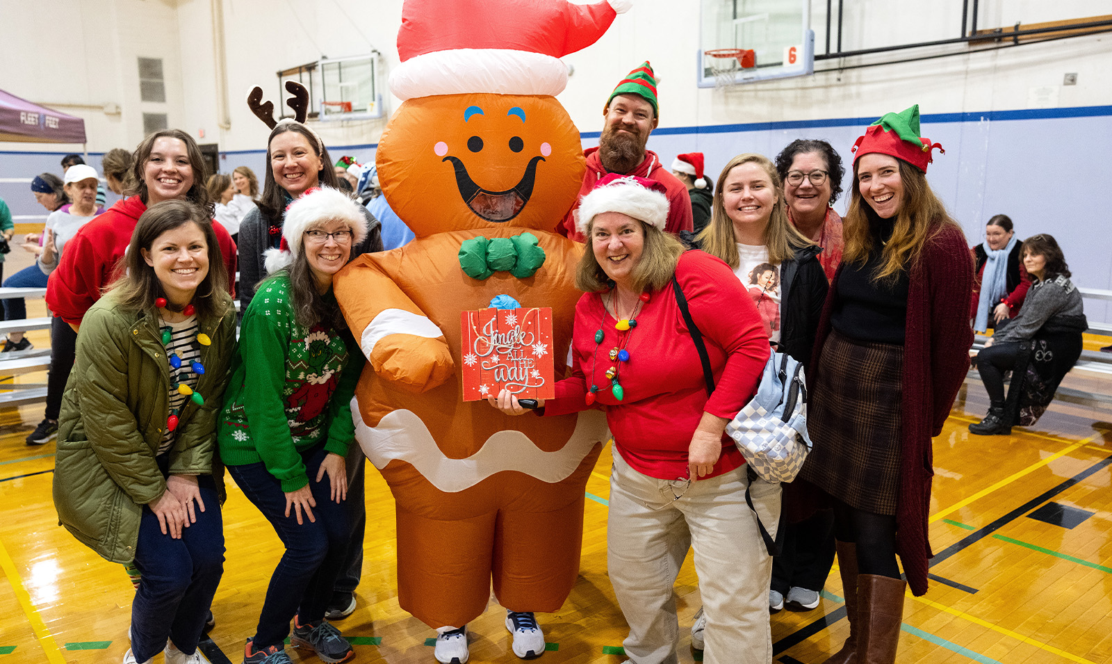 A group of people dressed up in Christmas costumes taking a picture with someone in a Gingerbread Man costume.