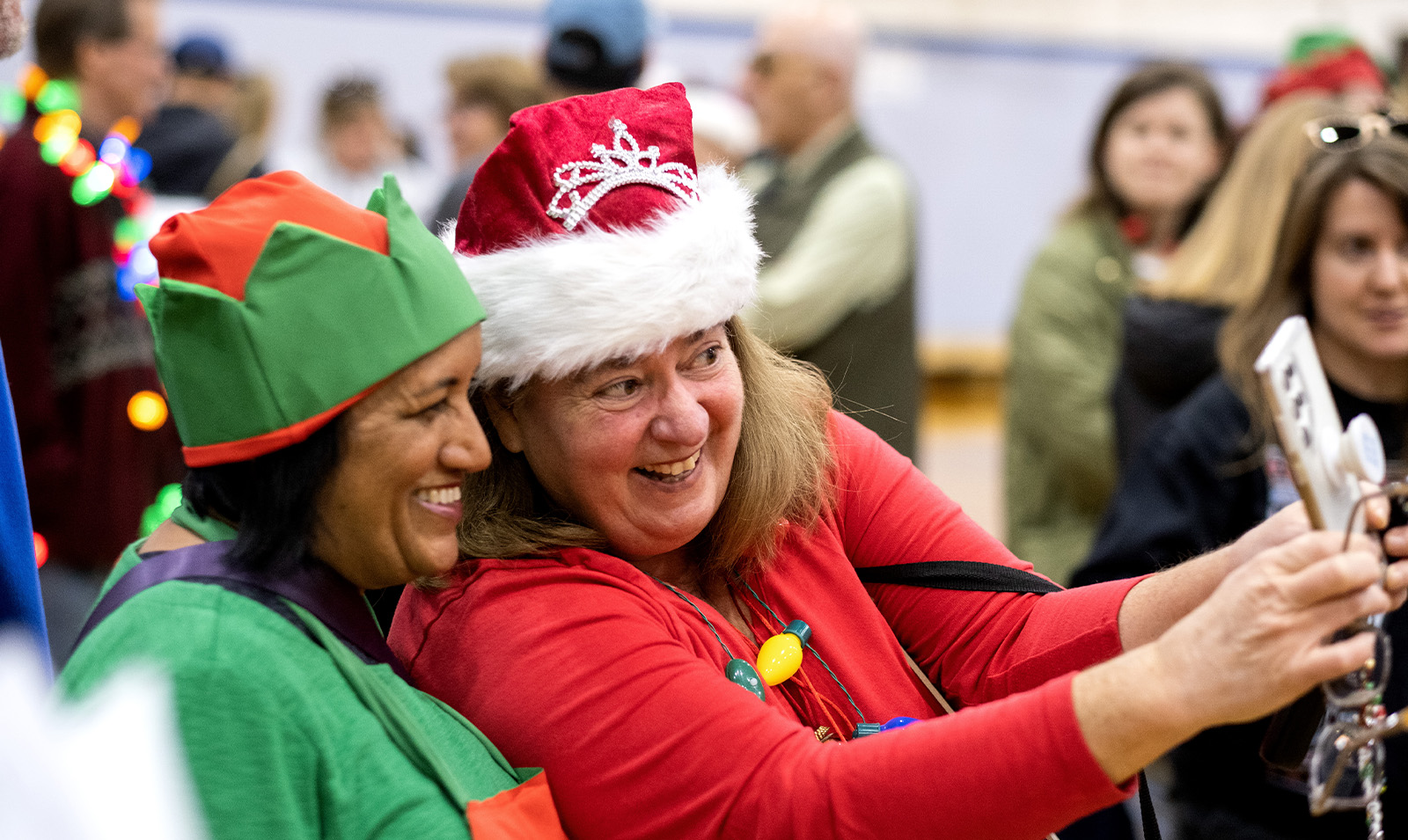 Two women, one wearing a Santa hat and the other dressed up as an elf, taking a selfie.