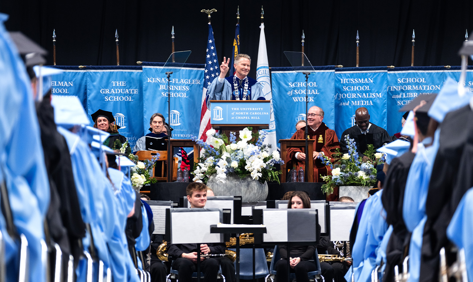 Chancellor Kevin M. Guskiewicz making a peace sign while speaking at Winter Commencement.