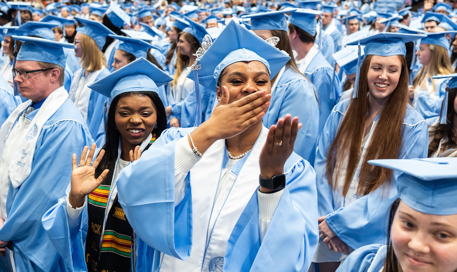 A graduate blowing a kiss with her hand at Winter Commencemnt.