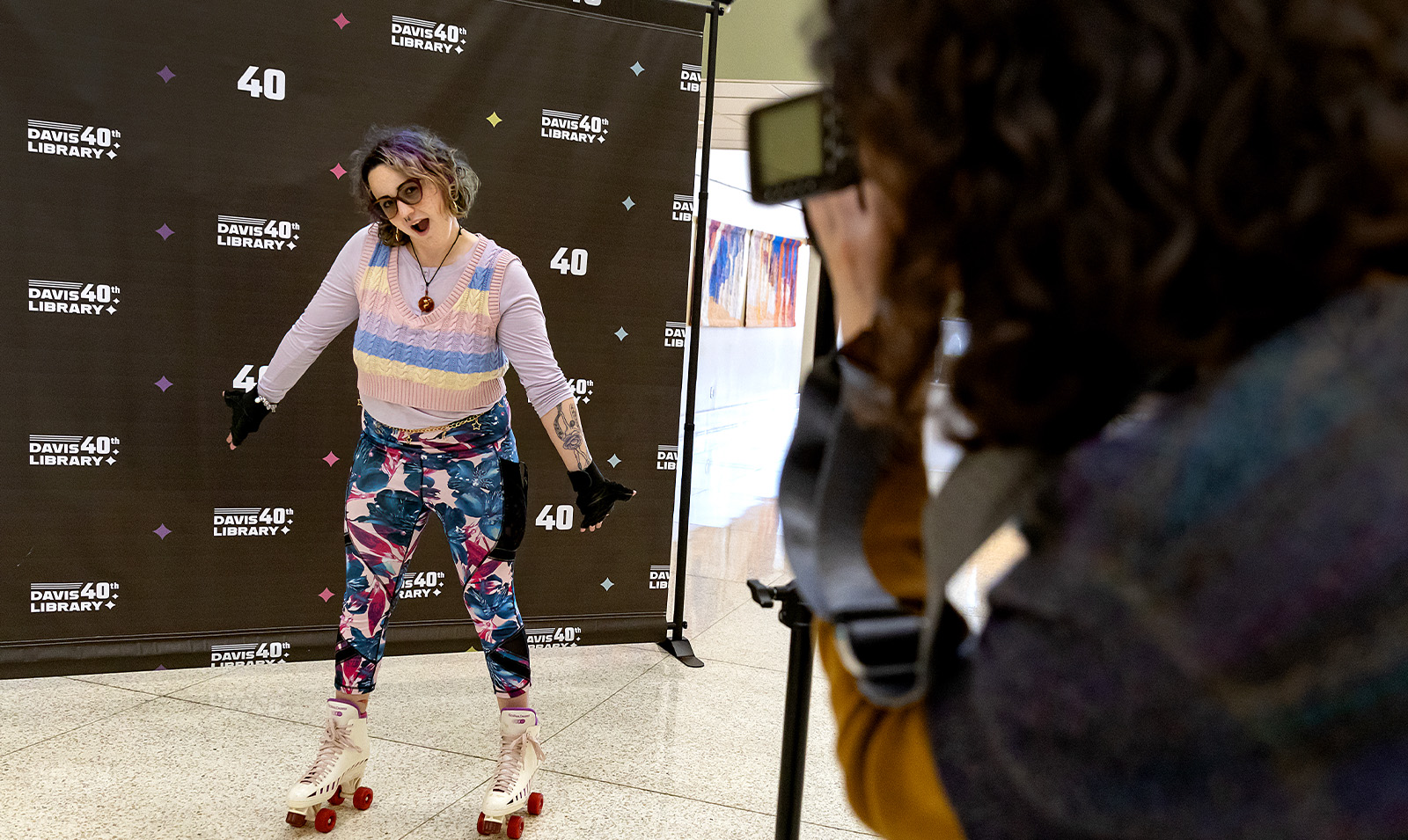 A student dressed in 1980s attire and rollerskates getting her picture taken.