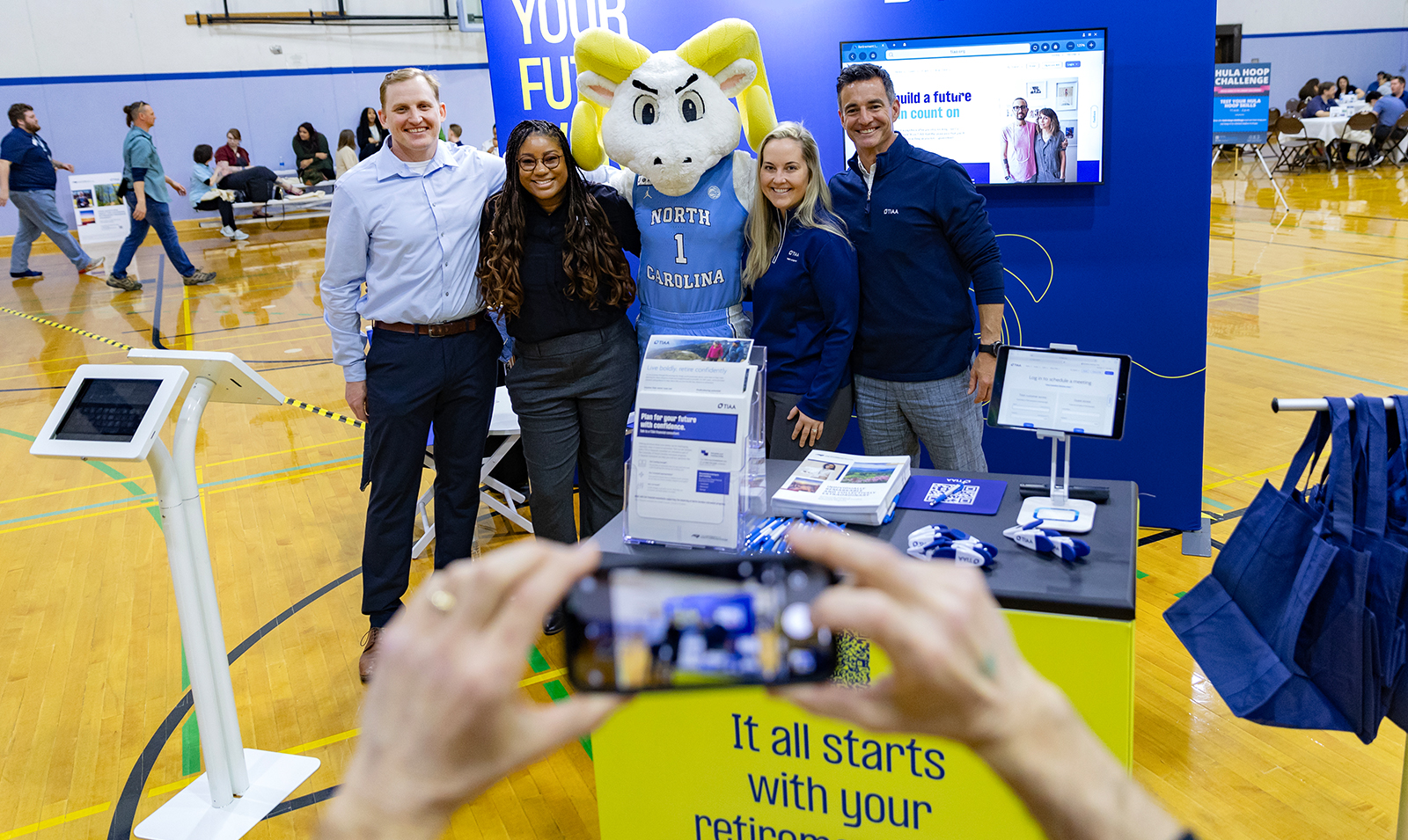 Four people posing with Rameses the mascot