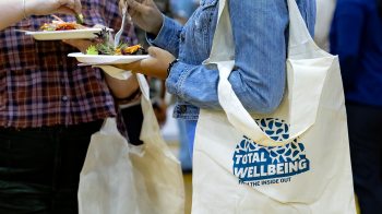 Woman walking with a Total WellBeing Expo tote bag