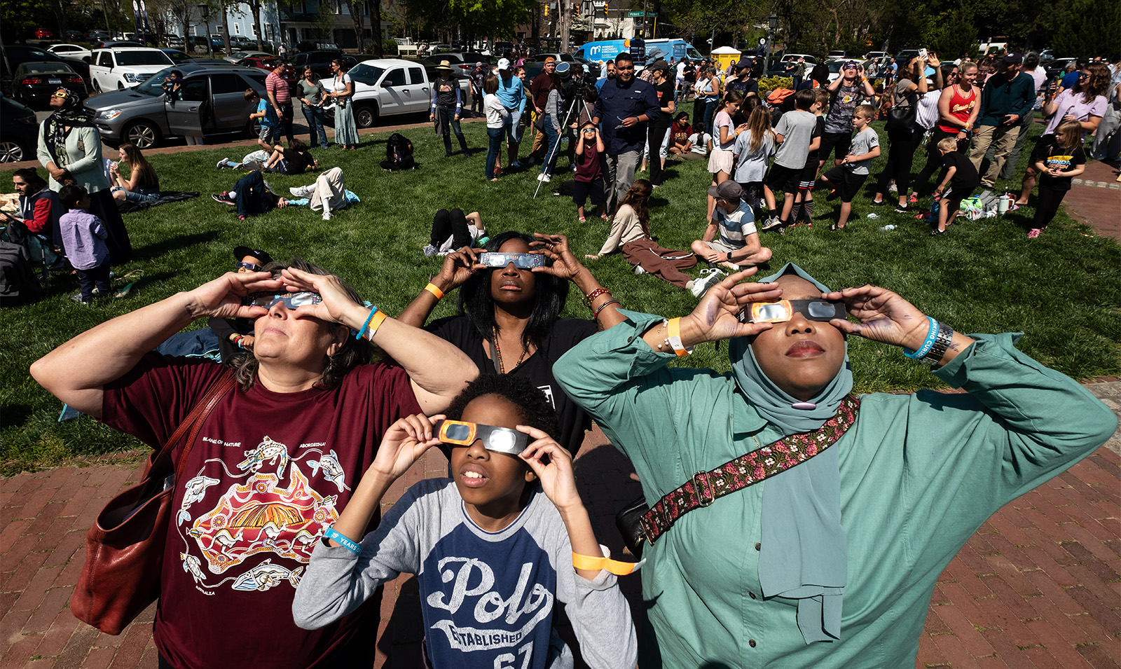 Group of four people wearing safety sunglasses while looking up at a solar eclipse.