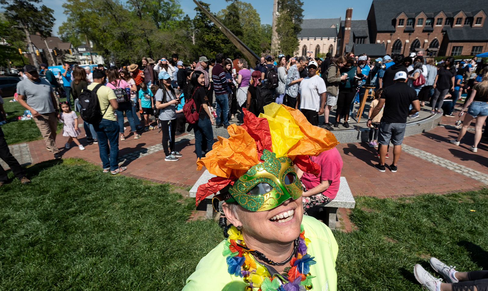 A woman wearing a costume looking at the solar eclipse. A crowd of people is seen behind her.
