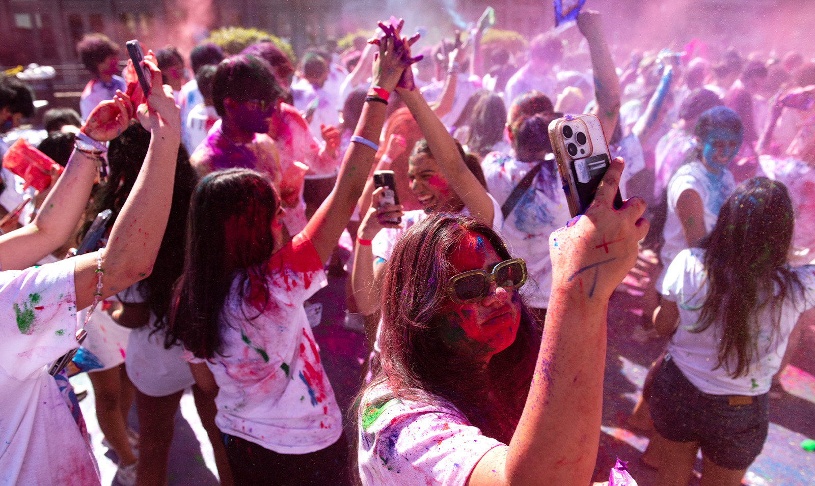 Crowd of students covered in paint celebrating Holi.