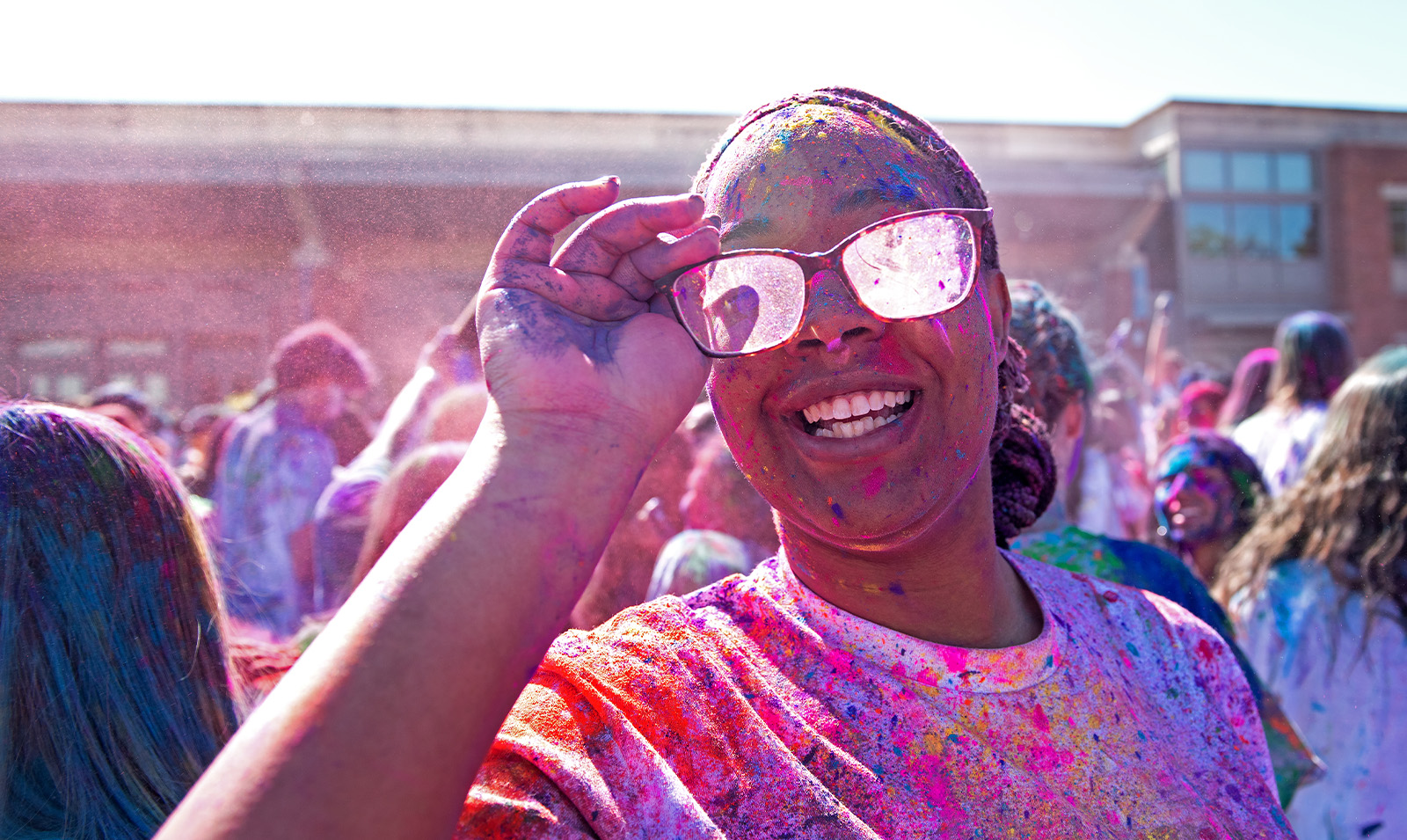 A student covered in paint celebrating Holi and smiling for a photo.