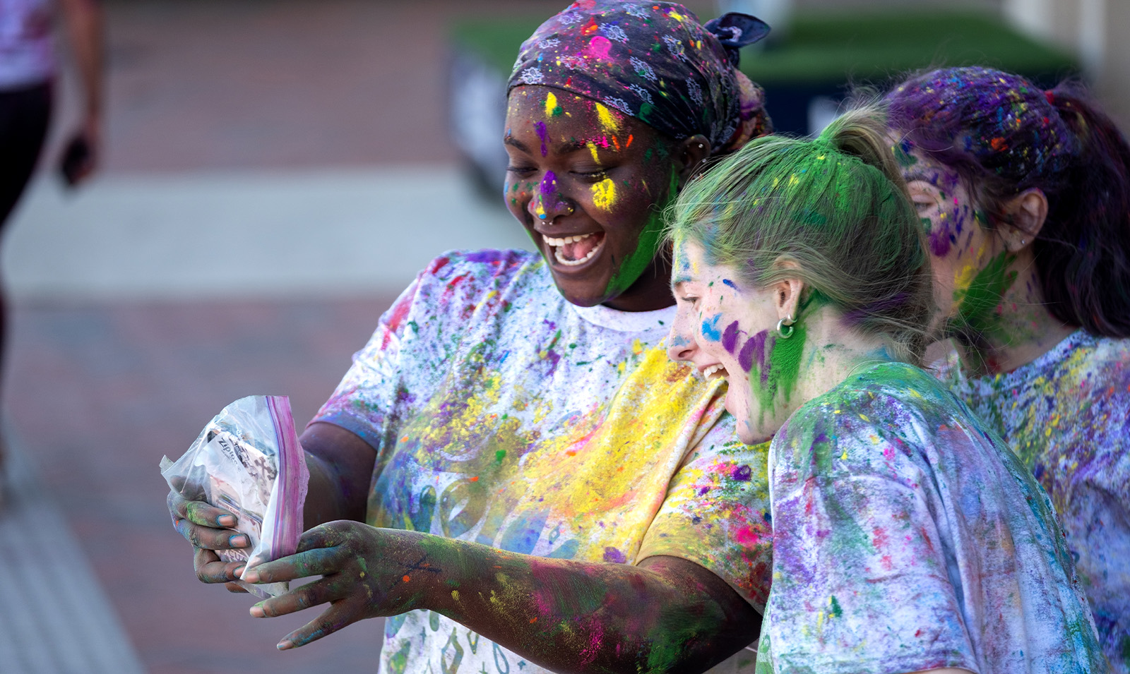 Two students covered in paint celebrating Holi.