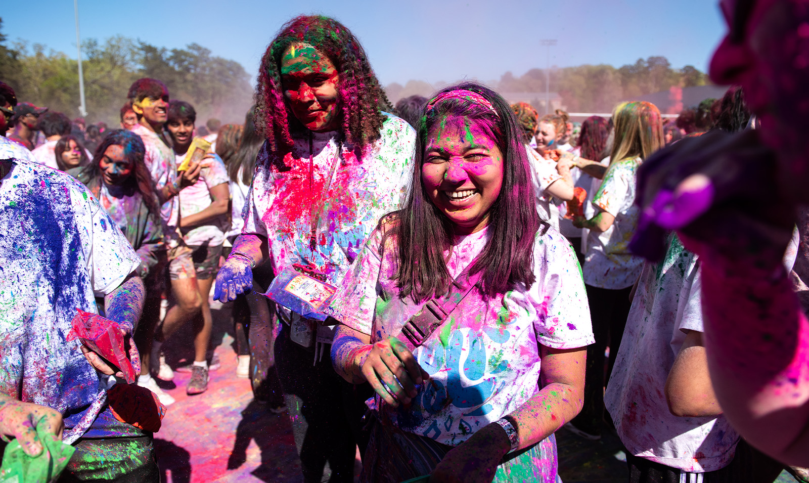 Two students covered in paint celebrating Holi.