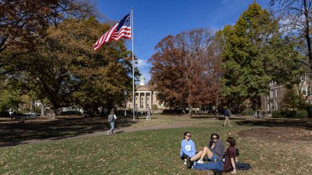 Students sitting on the lawn of Polk Place on a sunny day on the campus of UNC-Chapel Hill