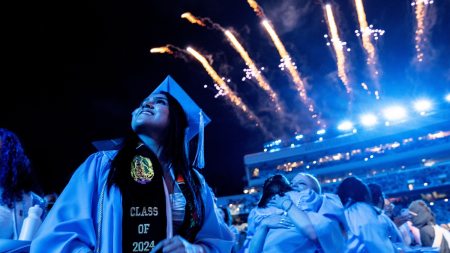 Graduate smiling as fireworks go off at Commencement at Kenan Stadium.