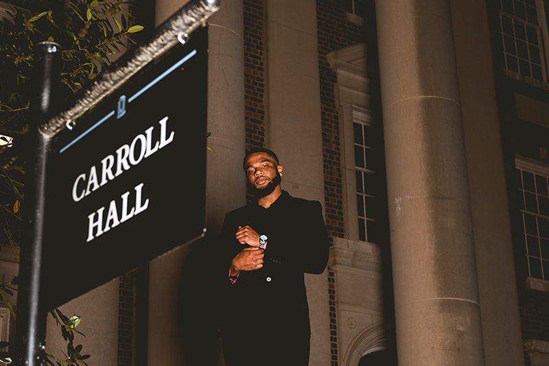 Cam Traylor in front of sign for Carroll Hall