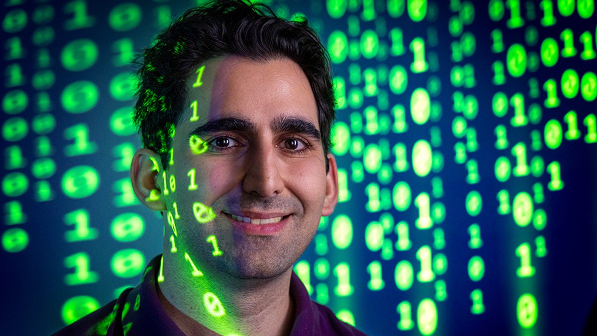 Saba Eskandarian standing in front of code being projected behind him.