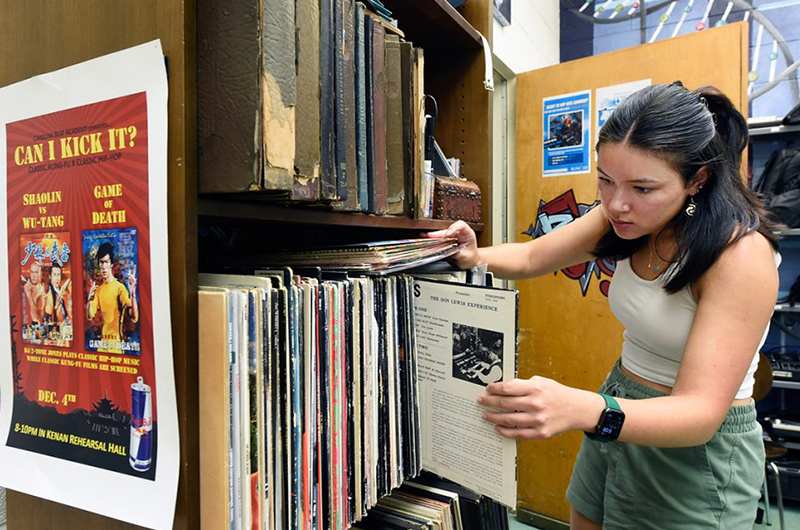 Student looks through vinyl collection, organized by two shelves.