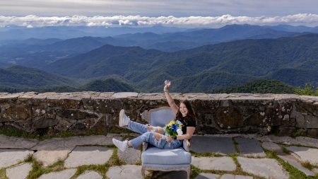 Gracie Elliott sitting sideways in a Carolina Blue chair with mountains seen in the background.