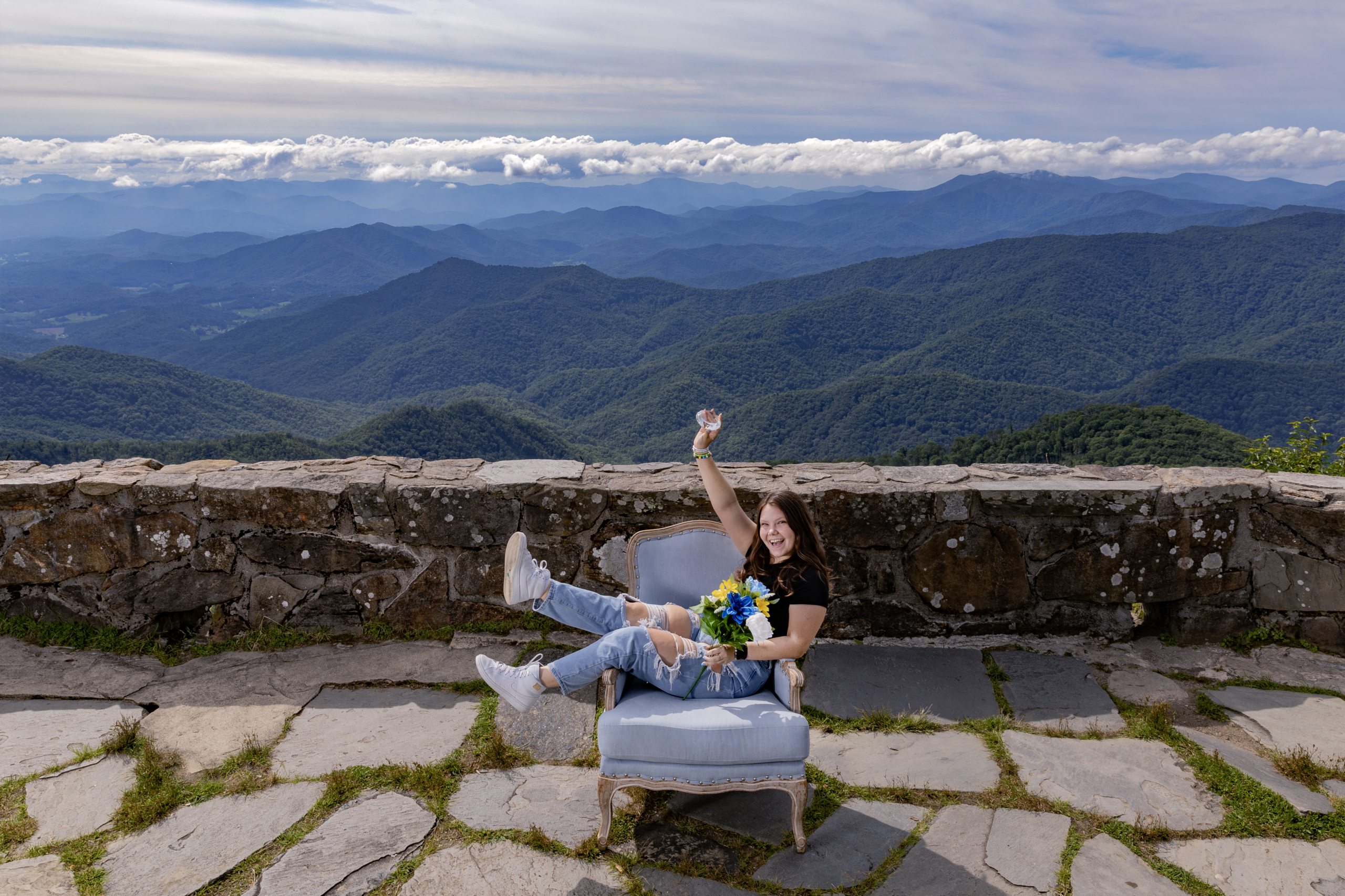 Gracie Elliott sitting sideways in a Carolina Blue chair with mountains seen in the background.