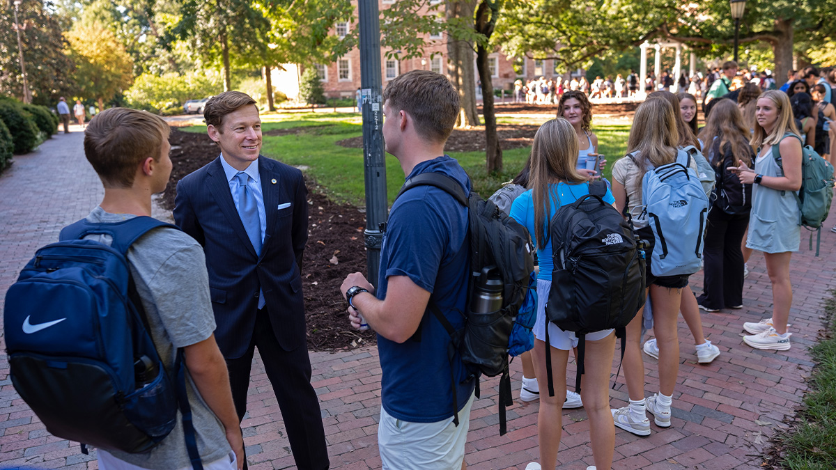 Chancellor Lee H. Roberts speaking to students waiting in line to take a sip from the Old Well.