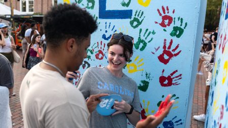 Two students handpainting a large mural at FallFest.