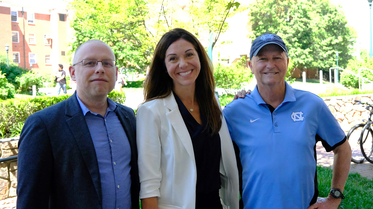 Jeff Greene, Erianne Weight and Anson Dorrance stand shoulder to shoulder.