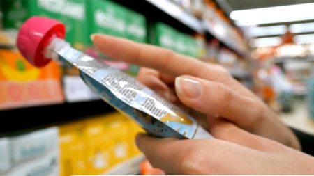 A woman's hand holding a pouch of baby food.