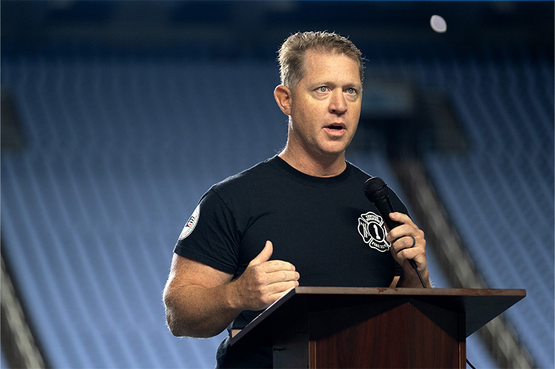 A man, John Dobrie, speaking to a crowd at a 9/11 Memorial Stair Climb event at UNC-Chapel Hill's Kenan Memorial Stadium.