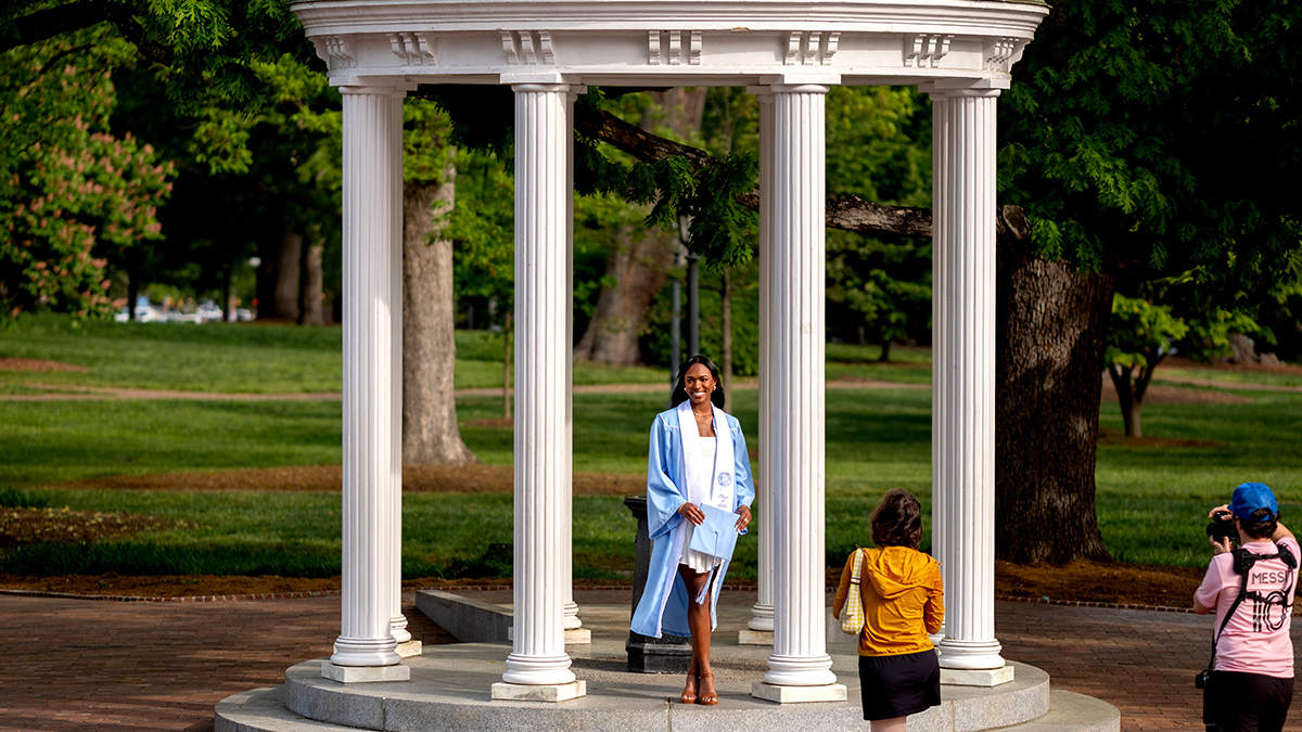 Student in a graduation gown at the Old Well.