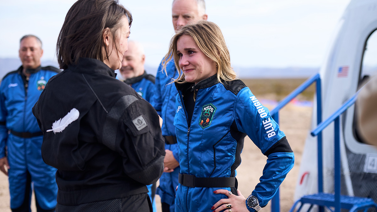 Karsen Kitchen in an astronaut uniform smiling as she speaks with a woman.