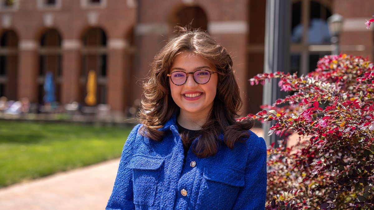 Sasha Surkin in blue jacket posing on UNC campus.