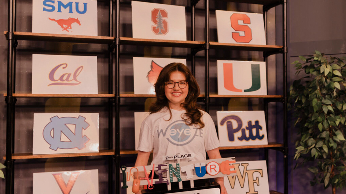 Sasha Surkin wearing UNC shirt posing in front of other university logos.