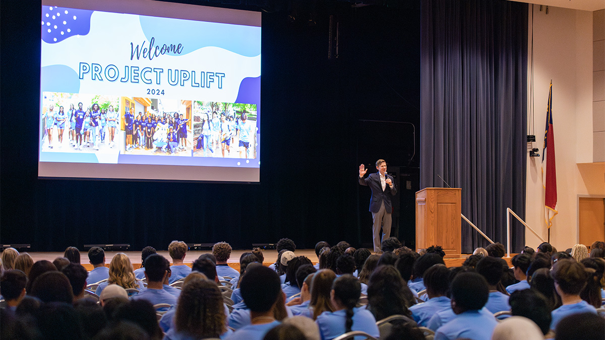 A man, Chancellor Lee H. Roberts, standing on stage in an auditorium and speaking to high schoolers attending a summer enrichment camp called Project Uplift at UNC-Chapel Hill.