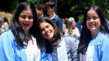 Twins Nathalie, Amaya and Nicole Martinez wearing graduation gowns.