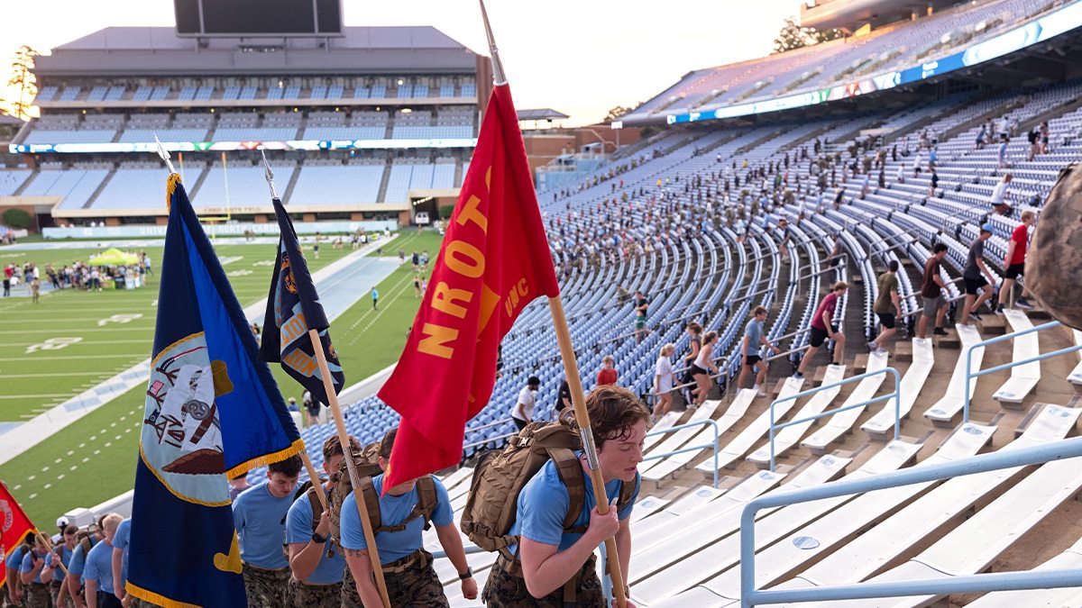 Individuals carrying flags up on the steps of Kenan stadium.