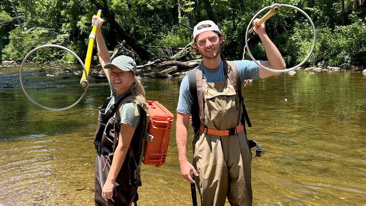 Tayton Alvis and Jenna Jordan holding backpack shockers during fish sampling at the Cullasaja River.