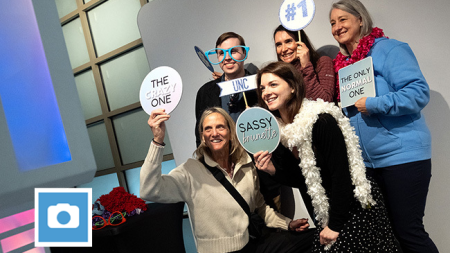 Carolina employees pose with signs at photo booth