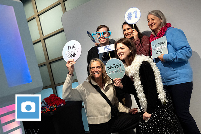 Carolina employees pose with signs at photo booth