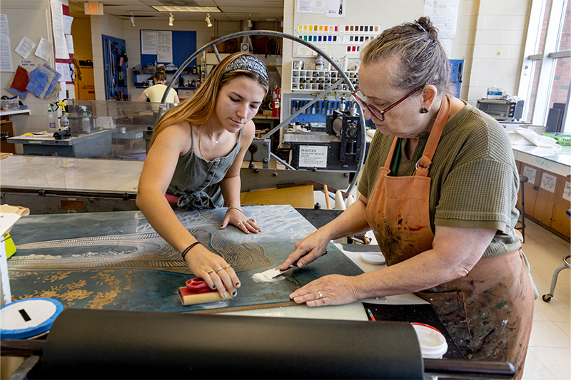 A student, Sophia Atkinson, and a professor, Beth Grabowski, looking at Atkinson's artwork.