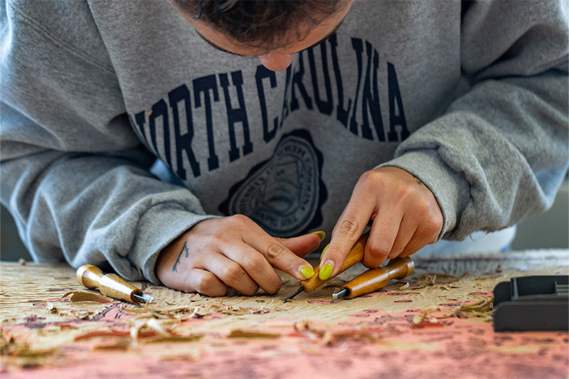 Close-up image of a student looking down at their artwork as they work.