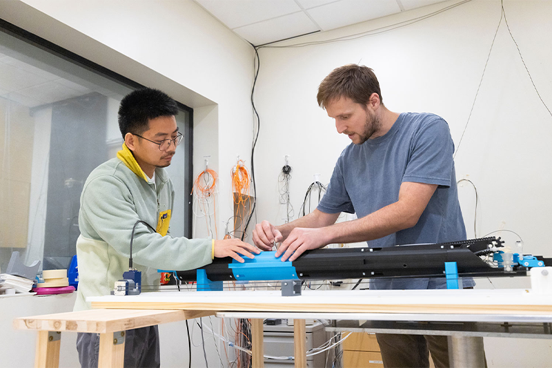 Neuroscientists Sheng Song (left) and Scott Tyler Albert work on a device in the Shih Lab.