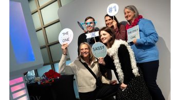 Carolina employees pose with signs at photo booth