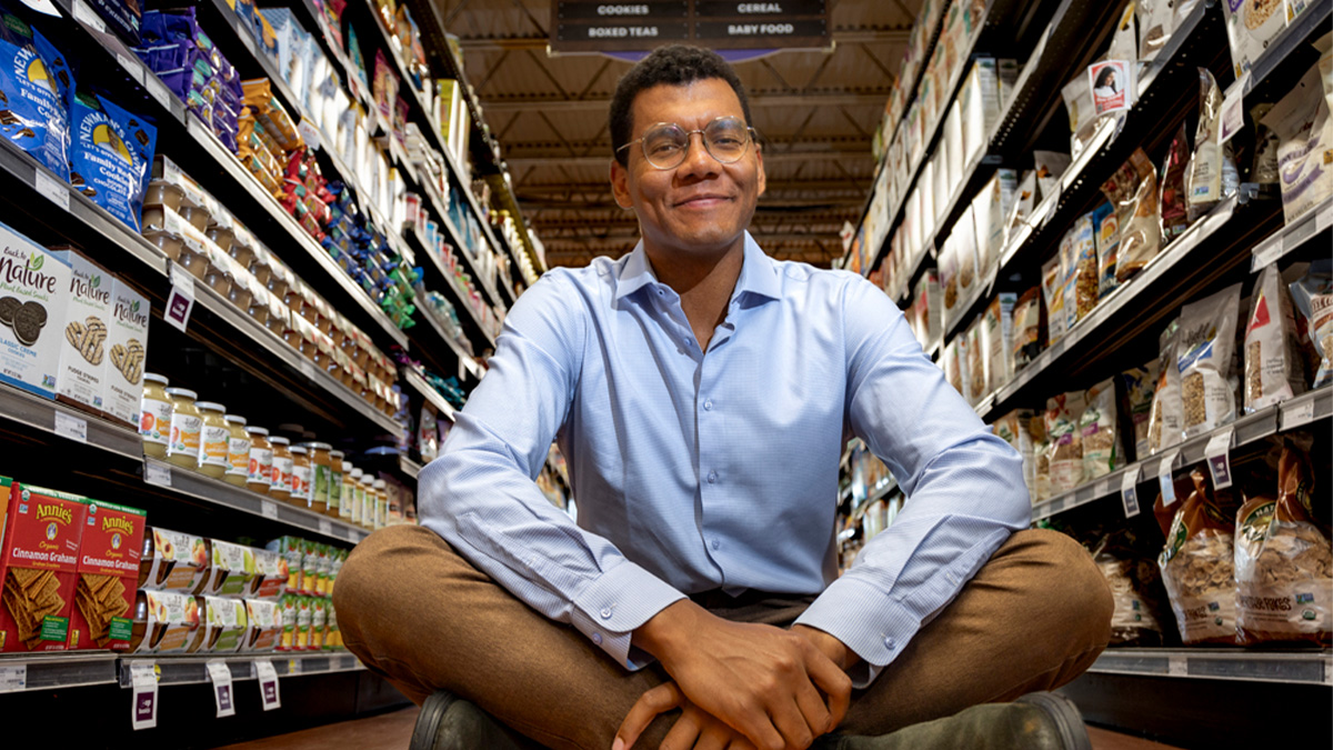 Emile Charles sitting down in the middle of an aisle inside of a grocery store.