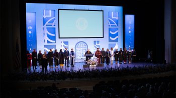 University leaders on stage at Memorial Hall during UNC-Chapel Hill's University Day celebration that included the installation of Lee H. Roberts. UNC System President Peter Hans is speaking from a podium.