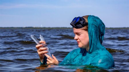 Peggy Mullin collects a water sample.