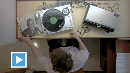 Bird's eye view of man sitting with record player.