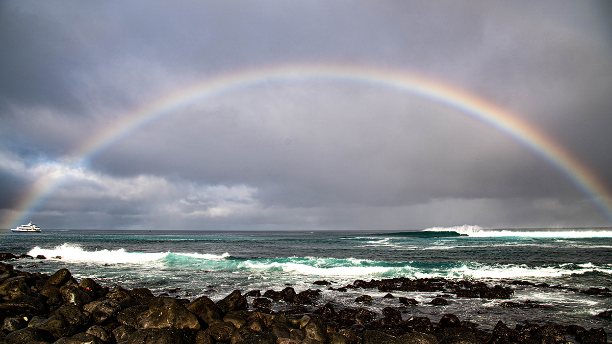 Rainbow stretching across Punta Carola Beach in San Cristobal, Galapagos.