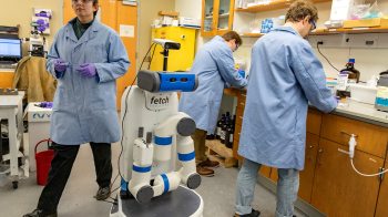 Three researchers in a lab with a robot.